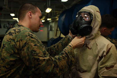 ABOARD USS PELELIU - Lance Cpl. Anthony C. Bocz, assessment consequence management team member, Chemical, Biological, Radiological and Nuclear Defense Platoon, 15th Marine Expeditionary Unit, adjusts the M50 field protective mask on a Marine from Weapons Company, Battalion Landing Team 3/5, 15th MEU, during a class on CBRN defense aboard the USS Peleliu, Oct. 4. The 15th MEU