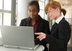 Photo of two people in front of a laptop