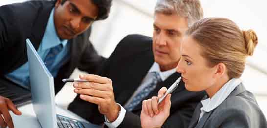 Two men and a woman at work reviewing content on a laptop