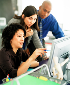 Woman showing two other employees something on the computer screen.