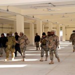 Afghan Border Police leaders walk through open bay barracks at the Islamcha garrison.  With them (in MultiCam uniform) is mentor Maj. Douglas Ingold. (USACE Photo/Mark Ray)