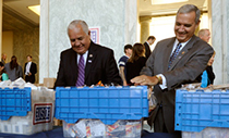 Rep. Sylvester Reyes (D.-Texas), left, and Rep. Jeff Miller (R.-Fla.) fill care packages for the troops in the foyer of the Rayburn House Office Building across from the Capitol in Washington, D.C., Sept. 11, 2012. (Photo credit: Mike Theiler / USO)