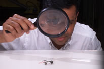 Man viewing sensor through magnifying glass