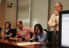 Photo of inventors with large-screen monitor.