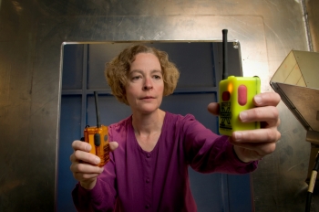 NIST engineer Kate Remley holds two Personal Alert Safety System (PASS) devices with wireless alarm capability. Photo copyright: Paul Trantow/Altitude Arts