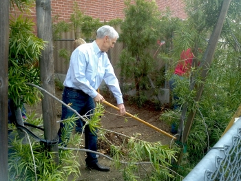 Secretary Bryson helping to start a community garden. He's holding a rake.