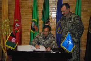 Brig. Gen. Aminullah Patyani, Commander of the Kabul Military Training Center (KMTC) accompanies Brig. Gen. Chan Wing Kai, Singapore Assistant Chief of General Staff (Operations) as he signs the guest book at the Hall of Honor located during a Singaporean visit to KMTC near Kabul, Afghanistan, April 22.