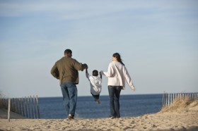 Parents & child holding hands on beach