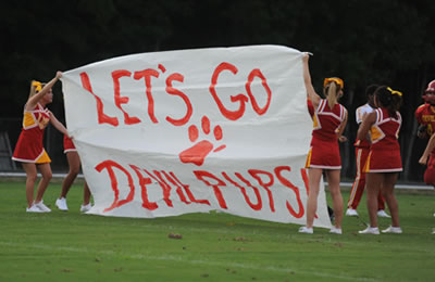 Cheerleaders holding banner for football team to run through.