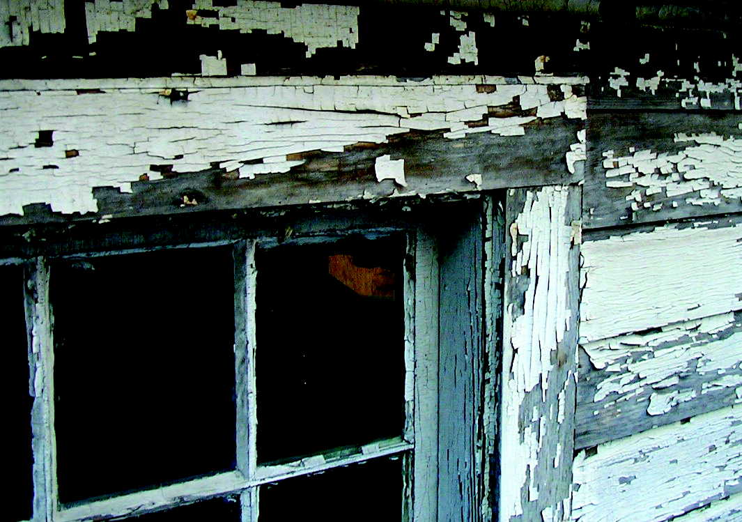 Very old looking window of a house showing serious signs of flaking of lead based paint.