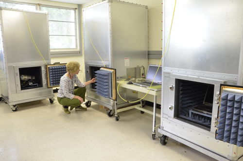 Researcher Kate Remley examines the middle chamber containing a repeater unit in a “one hop” communications test. The PASS is in the cabinet at left, and the base station is in the cabinet at right.