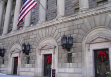 U.S. Department of Commerce Fourteenth Street main entrance with holiday wreaths and bows above doors. Click for larger image.