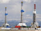 Photo of three natural gas drilling rigs.