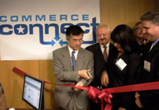 Locke with scissors cutting ribbon at ceremony. Click for larger image.