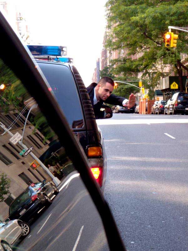 A Diplomatic Security special agent gestures to motorists to stay away from the DS motorcade transporting Britain's Prince Harry as they travel through New York City.