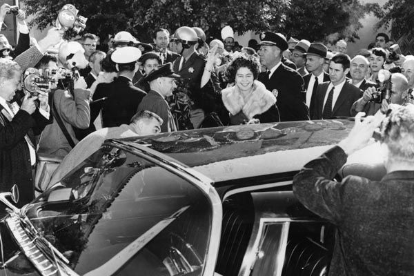 November 21, 1958:  Special Agent Leo Crampsey bends and peers into waiting limousine as Her Royal Highness Queen Frederika of Greece waves upon arrival in Los Angeles. (Source: DS Records)