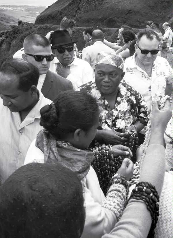 1967:  President Philibert Tsiranana of Madagascar (center) visits Pali, Honolulu, Hawaii.  His Office of Security detail includes SY Special Agents Hudgins Smith (left in dark suit and dark glasses) and William DeCourcy (right in Hawaiian shirt and dark glasses).  (Source: DS Records)