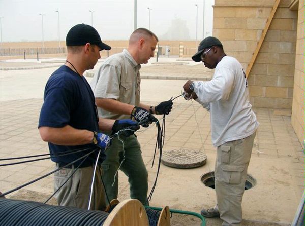 2008:  A DS Security Technology team from the Countermeasures Directorate installs technical security systems at the U.S. ambassador's residence in Baghdad, Iraq.  A security engineering officer assists U.S. Navy Seabees James Griffith (left) and Dhafir Freeman (right) in installing cabling.  
(Source: DS Records)
