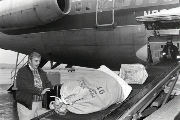 Circa 1985: A DS diplomatic courier loads pouches at a Washington, D.C. airport. Diplomatic couriers spend tens of thousands of hours annually delivering tens of millions of pounds of classified diplomatic pouch material by air, sea, and over land, including palletized equipment for new embassy construction. (Source: DS Records)