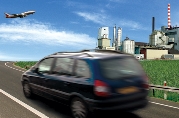 Photo of car driving down a road with an integrated biorefinery in the distance and an airplane flying overhead