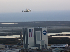 Discovery and the SCA fly past the Vehicle Assembly Building