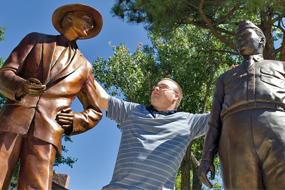 young male student by statues of Groves and Oppenheimer