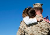 Child with flag hugging a man in fatigues