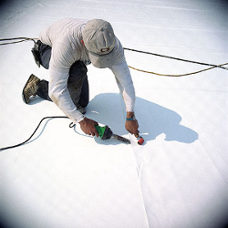 Photograph of a man working on a white cool roof.