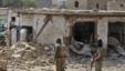 Pakistani men check the damage caused by a car bomb explosion, while army soldiers gather at the site in the town of Darra Adam Khel in the troubled Khyber Pakhtunkhwa province bordering Afghanistan, October 13, 2012. 