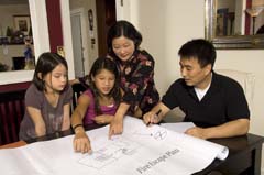 Asian-American family; mother and older daughter pointing at plan