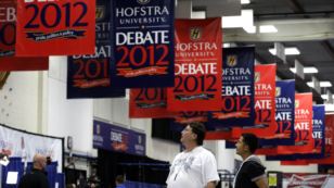 Billy Koske, left, and Jose Reyes look at signs hanging in the media filing center before Tuesday's presidential debate between President Barack Obama and Republican presidential candidate, former Massachusetts Gov. Mitt Romney, October 15, 2012.