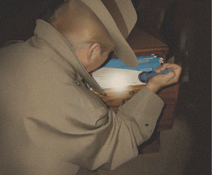 Photo of a detective shining a flashlight on a file cabinet.