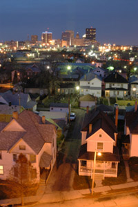Photo of a cityscape, starting with suburban homes in front and extending out to a full city skyline.