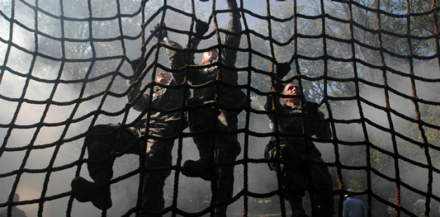 Soldiers climbing cargo net obstacle