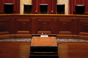Close-up of Courtroom lectern looking toward the Bench and five of the nine Justices' chairs