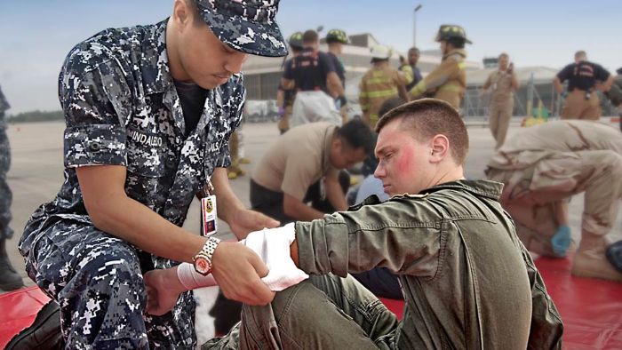 A Hospital Corpsman bandages a Naval Aircrewman during an emergency drill.