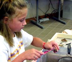 (photo) A kid scrubs an artifact with a toothbrush. (NPS)