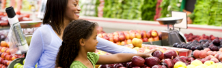 Mother and daughter looking at fruit in a grocery store