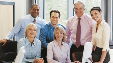 Members of a small business posing around a co-worker's desk