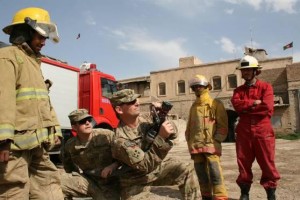 Staff Sgt. Vern Grilliot (front), a military police officer with the 58th Military Police Company attached to 1st Squadron, 10th Cavalry Regiment, 2nd Brigade Combat Team, 4th Infantry Division, and 1st Lt. Jeffrey Parrott (behind), chief of information operations for 1st Sqdn., 10th Cav. Reg., demonstrate how to properly control the hose to firefighters from the Kandahar Fire Department at their firehouse.