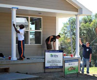 Headquarters and Headquarters Company, 40th Military Police Internment and Resettlement Battalion Soldiers Spc. Jordan Simpson, Pfc. Travis Wilt, and Cpl. Raymond Gordineer paint porch columns at the Habitat for Humanity home site Oct. 1 in Kansas City. 