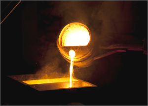 Molten metal pours from lathe during iron casting.