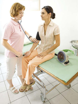 A nurse checking a woman’s blood pressure 