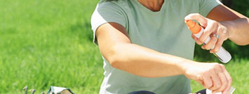 Photo: Woman spraying insect repellent on arm