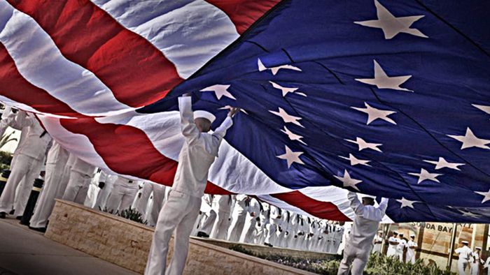 Sailors open an American flag before a Memorial Day event.