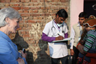 Secretary Sebelius listening to a field staff nurse taking a history from a child's family. Rural village about 50km from Delhi, India.