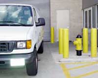 (Fig. 2.14) This hydrant should not have been located where it is likely to be blocked. Loading docks, by nature, will likely have vehicles parked. This is an example of building a potential deficiency into a facility.  The truck could prevent use of the large pumper connection or cause the base to be kinked when used. Note the yellow bollards which protect the hydrant from vehicle collision.