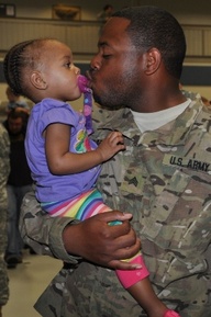 Sgt. Quintin Clark, of Kansas City, gives his daughter, Qadance, a kiss after the welcome home ceremony at Ike Skelton Training Site. When Clark left, Qadance was only three months old. (Photo by Sarah Lupescu/Missouri National Guard)