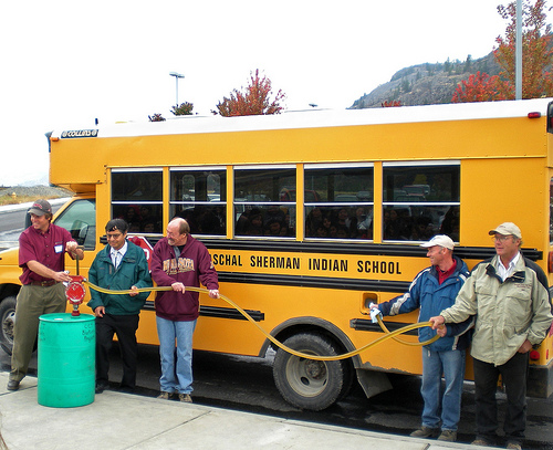 A biodiesel blend containing oil from winter canola is pumped into a Paschal Sherman Indian School bus. Pictured left to right: Washington State University extension specialist Phil Linden, Colville Confederated Tribes member Ernie Clark, ARS agronomist Frank Young, ARS technician Larry McGrew, and local grower Ed Townsend. Photo by Carla Des Voigne.