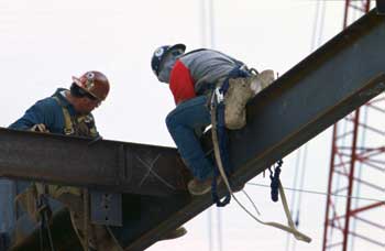 Photo of two workers on a construction beam.